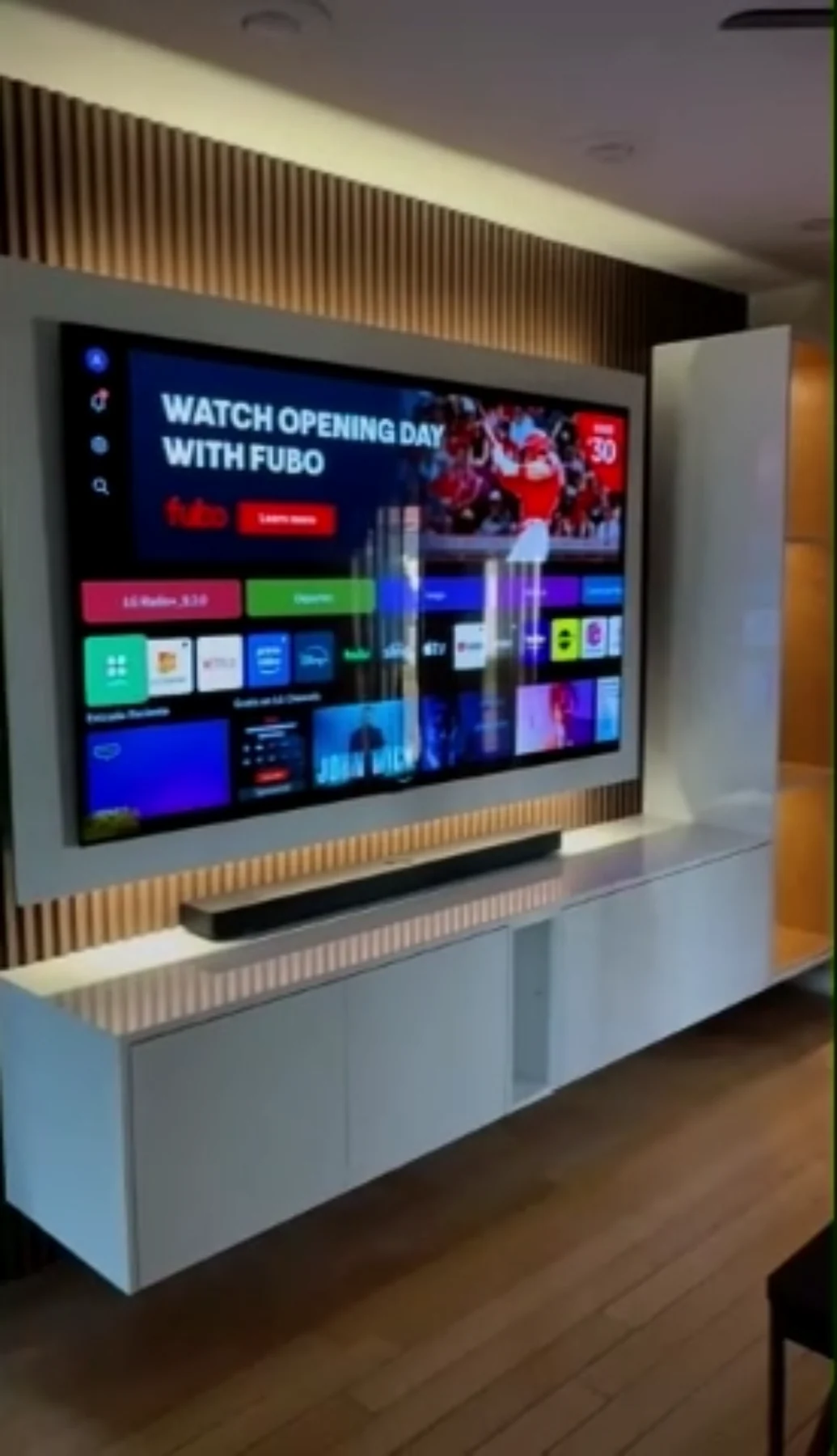 Custom media wall with television, white cabinetry and warm vertical wood-slat detailing.