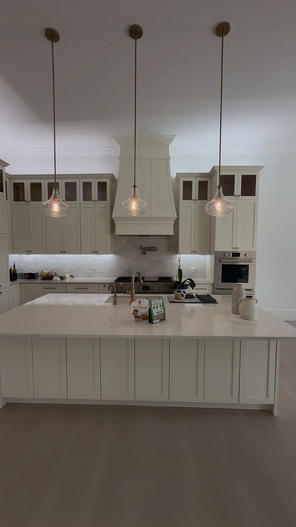 Front view of a white custom kitchen with island, range hood and integrated cabinetry.