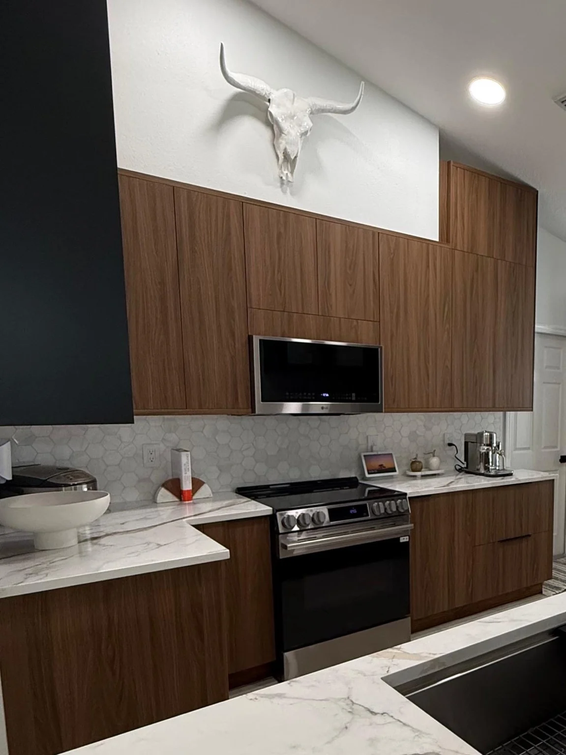 Custom walnut-tone kitchen cabinetry with integrated microwave, stone counters and warm architectural detailing.