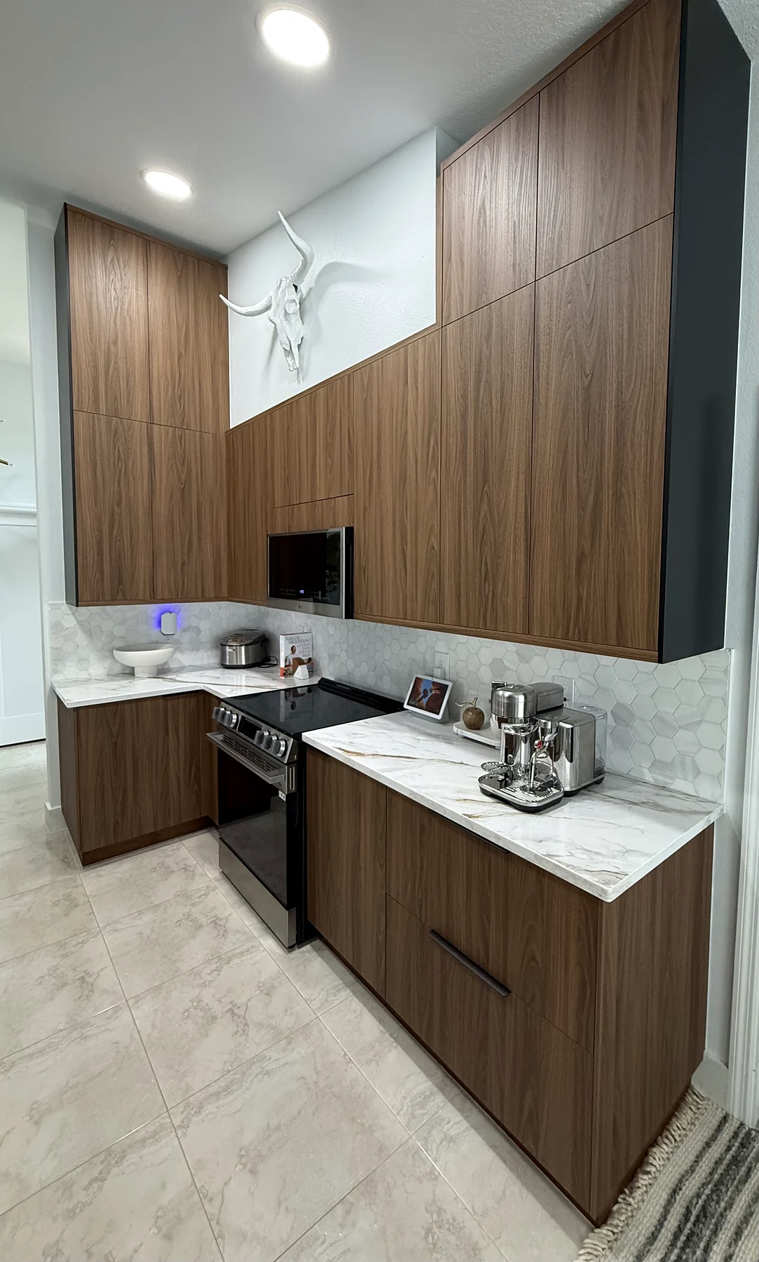 Custom wood kitchen cabinetry with tall panels, stone counters, microwave and range.