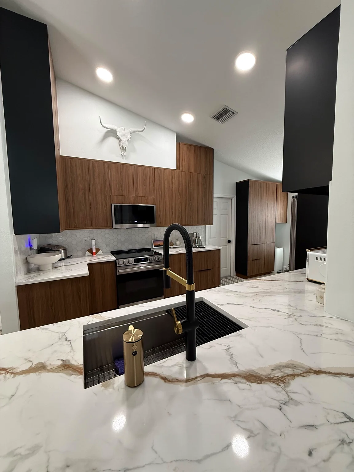 Modern wood kitchen with marble-look island and black and gold faucet, an HD Carpentry project.